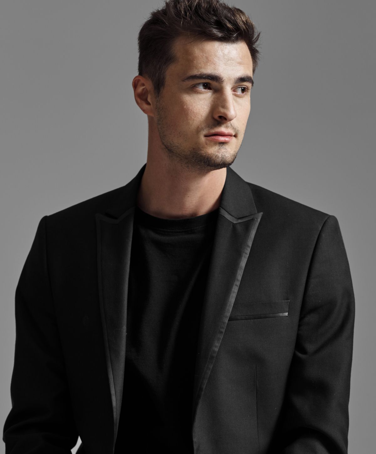 Man in black blazer against gray background.