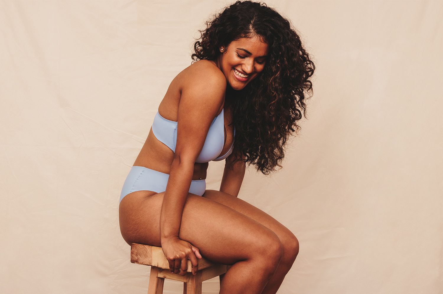 Person with curly hair sitting on a stool.