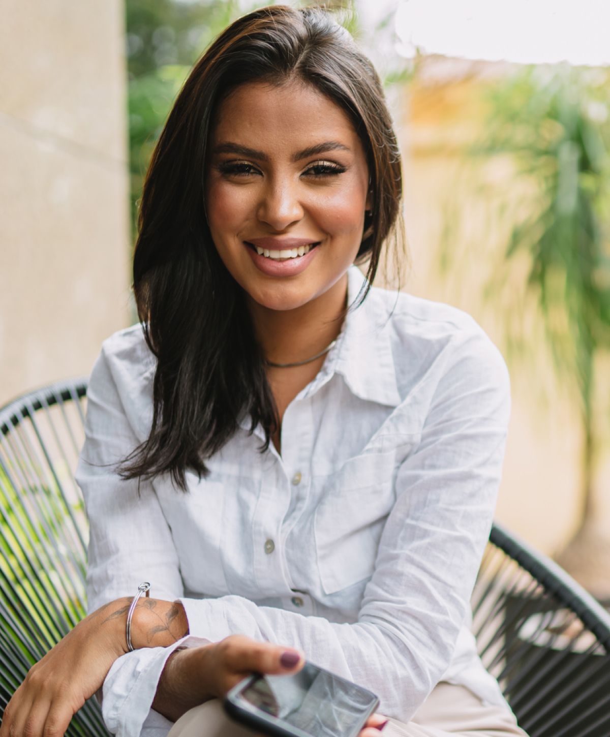 Smiling woman seated with smartphone in hand.